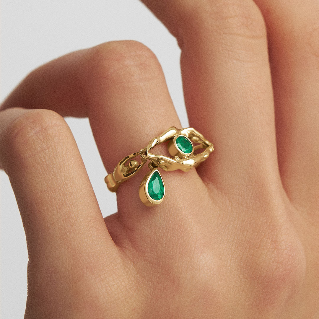 Model wearing eye ring with tear and bodies in 18k gold and emeralds
