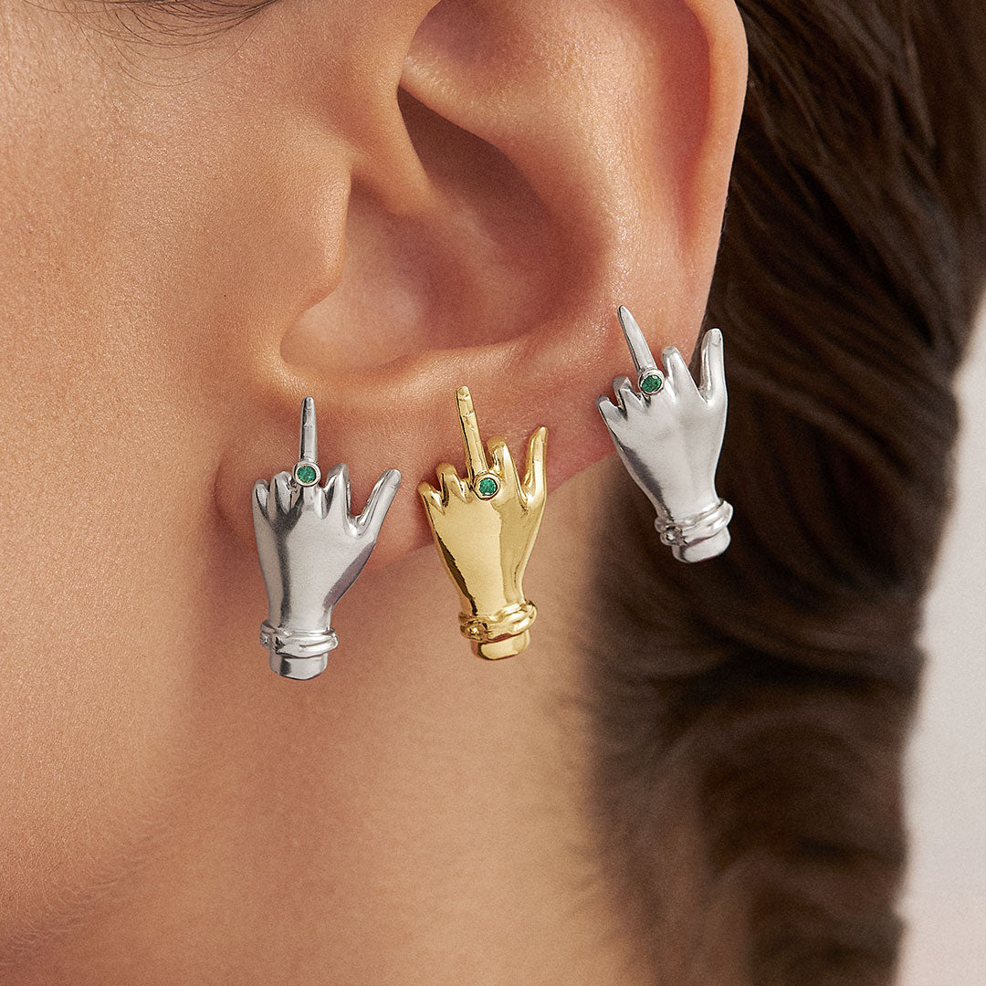 Model wearing sterling silver middle finger earrings with 18k gold plating and emerald