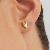 Model wearing 18k gold mini middle finger earring adorned with diamond