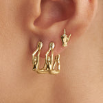 Model wearing 18k gold middle finger earrings adorned with diamond and female bodies