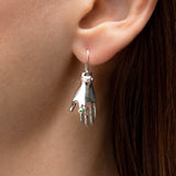 Model wearing a sterling silver earring with a hand and emerald