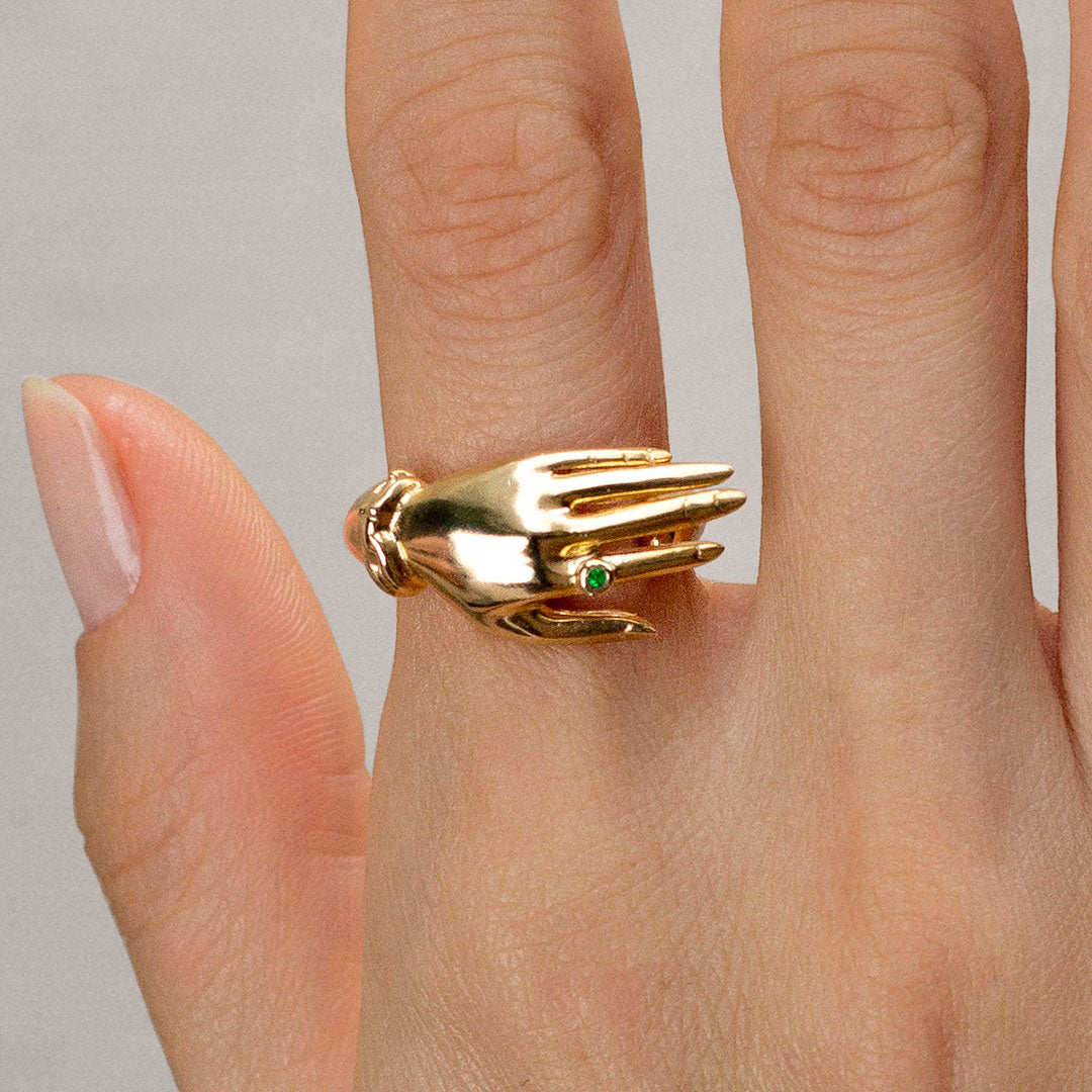 Model wearing a sterling silver ring with 18k gold plating of a hand with an emerald