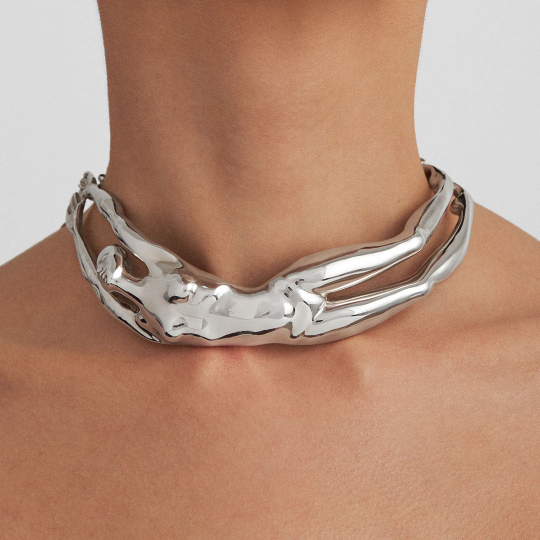 Model wearing a sculptural choker of a female body in sterling silver