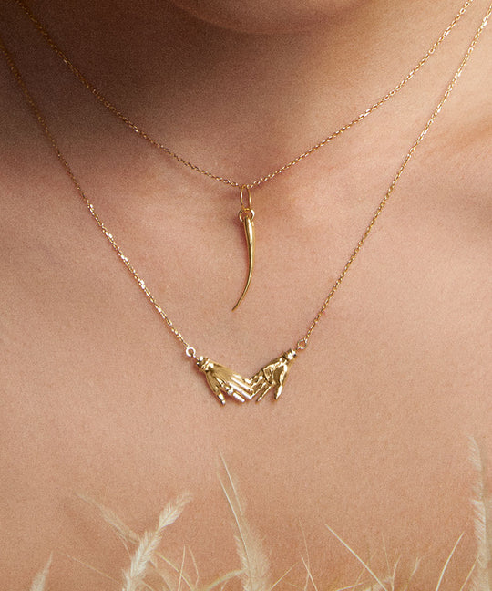 Model wearing 18k gold eyelash pendant on a chain