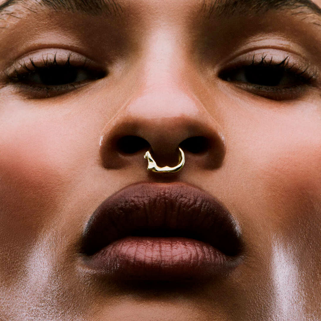 Model wearing a faux piercing of a female body in sterling silver with 18k gold plating