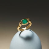 18k gold ring of hands with diamonds and oval emerald
