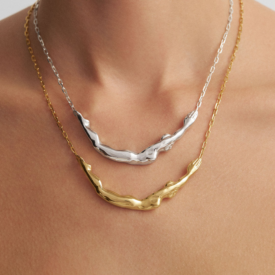 Model wearing necklaces of female bodies in sterling silver with 18k gold plating