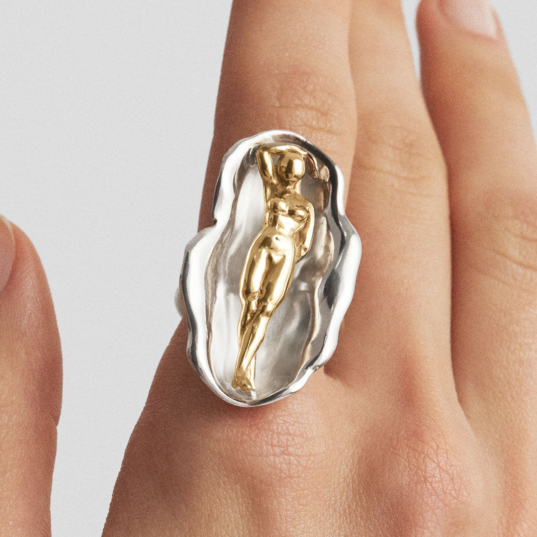 Model wearing a sterling silver ring with 18k gold plating of Venus in a shell